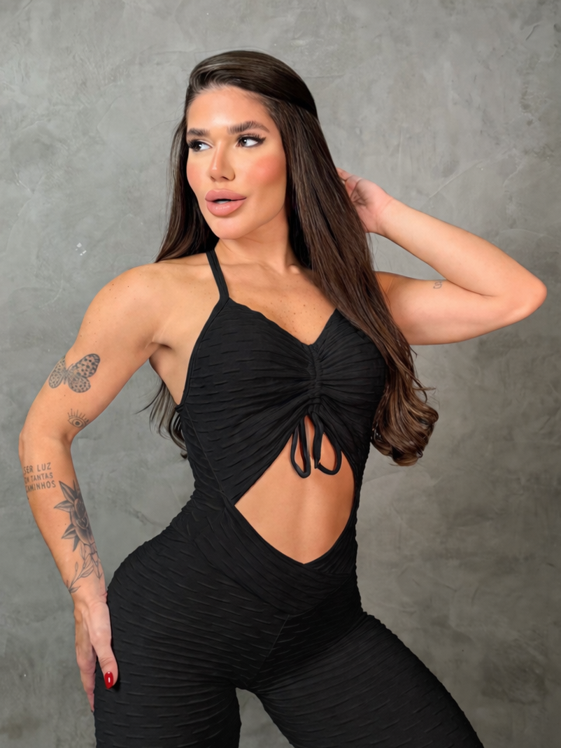 Woman wearing a black outfit with cut-out design against a gray background